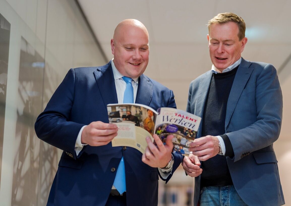 Overhandiging ABU Inspiratiegids minister Aartsen en Bruno Bruins bladerend in gids