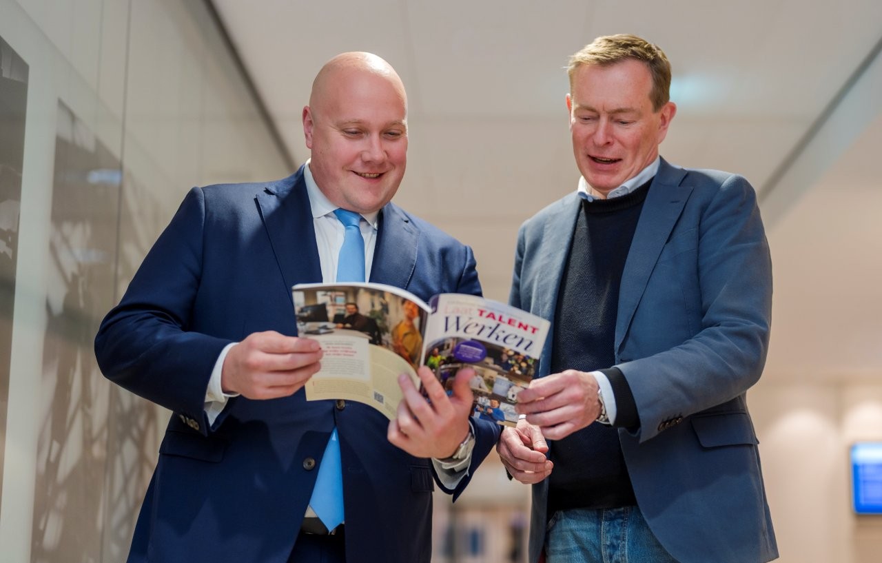 Overhandiging ABU Inspiratiegids minister Aartsen en Bruno Bruins bladerend in gids